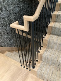 a staircase with a black railing and wallpaper